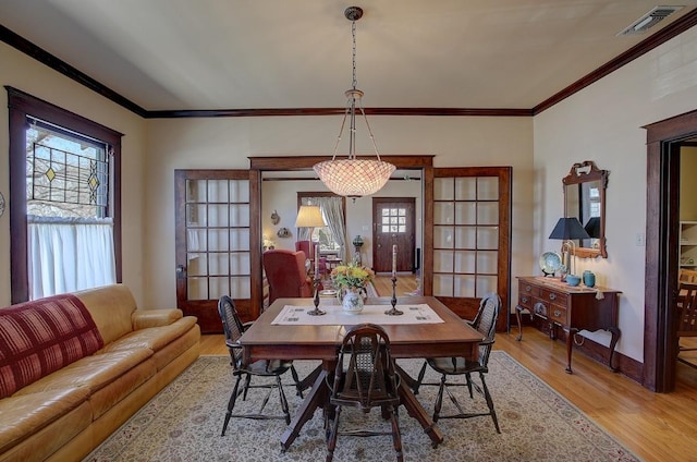 dining room featuring light wood-style floors, visible vents, plenty of natural light, and crown molding