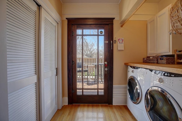 washroom with light wood-type flooring, cabinet space, and washer and clothes dryer