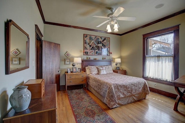 bedroom with a ceiling fan, crown molding, baseboards, and wood finished floors