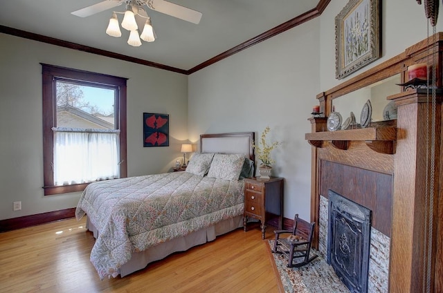 bedroom featuring ornamental molding, a fireplace, baseboards, and wood finished floors