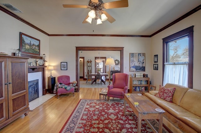 living room featuring crown molding, a wealth of natural light, visible vents, and a fireplace