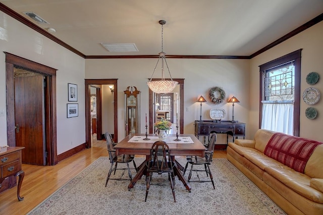 dining room with baseboards, visible vents, crown molding, and light wood finished floors