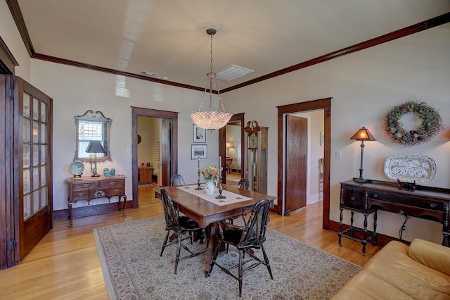 dining space featuring visible vents, crown molding, light wood-style flooring, and baseboards