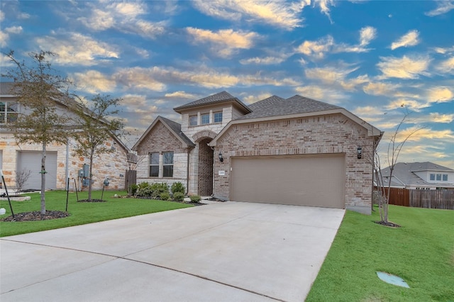 view of front of property with brick siding, concrete driveway, an attached garage, fence, and a front lawn