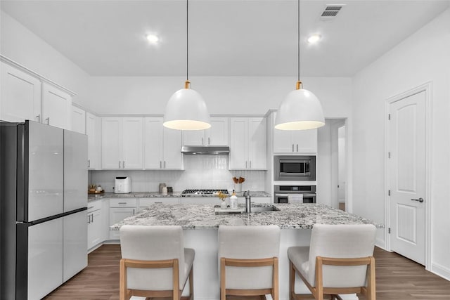 kitchen with appliances with stainless steel finishes, dark wood-style flooring, white cabinetry, and decorative backsplash