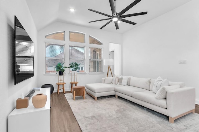 living room featuring vaulted ceiling, baseboards, light wood-style flooring, and a ceiling fan