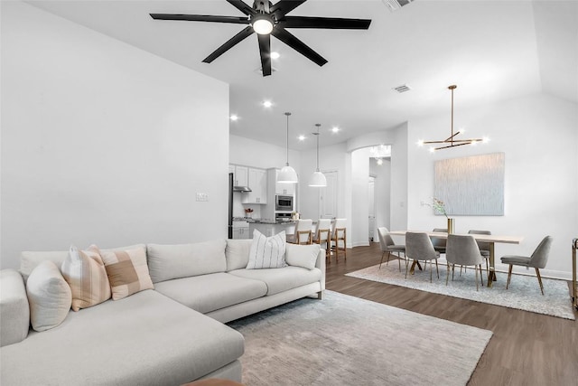 living room featuring ceiling fan with notable chandelier, dark wood finished floors, visible vents, and recessed lighting