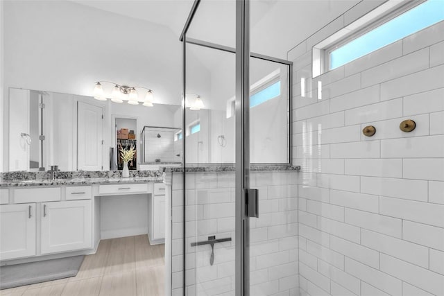 full bath with double vanity, a stall shower, a sink, and a wealth of natural light