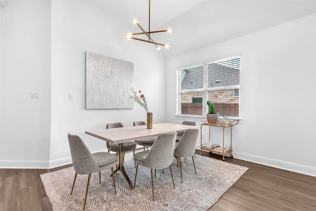 dining room with a chandelier, lofted ceiling, baseboards, and wood finished floors