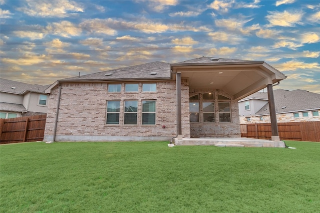 rear view of property with a yard, a patio area, and fence