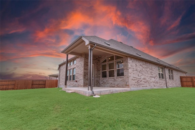 rear view of property featuring a patio, a yard, a fenced backyard, and brick siding