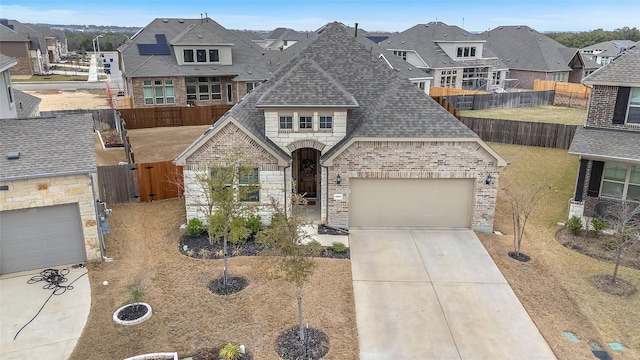 french country style house with brick siding, fence, driveway, roof with shingles, and a residential view