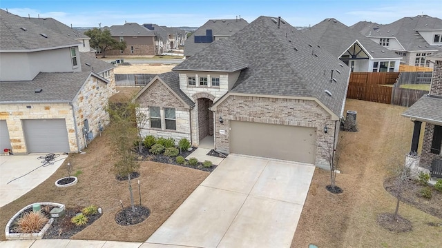 french provincial home with a residential view, stone siding, roof with shingles, and driveway