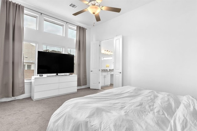 bedroom with a ceiling fan, connected bathroom, visible vents, and light colored carpet