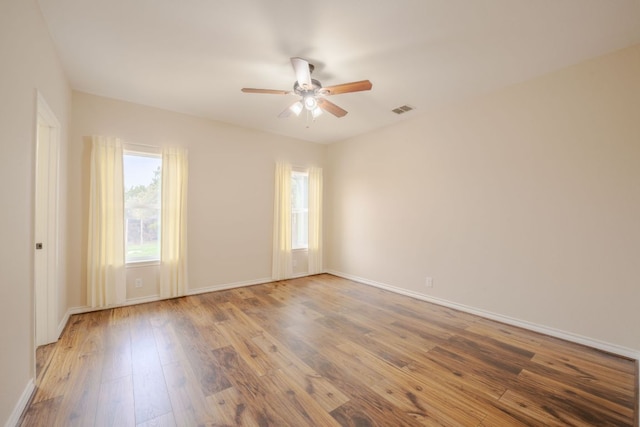 empty room with ceiling fan, visible vents, baseboards, and hardwood / wood-style floors