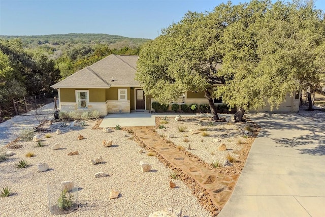 view of front of property with fence, driveway, stucco siding, a garage, and stone siding