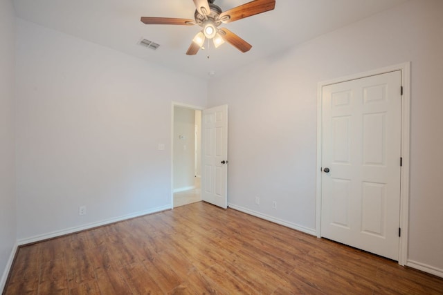 unfurnished room featuring a ceiling fan, wood finished floors, visible vents, and baseboards