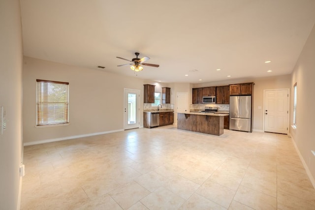 kitchen with tasteful backsplash, open floor plan, stainless steel appliances, and a sink