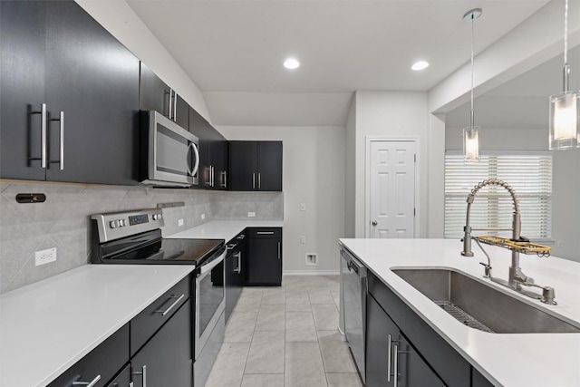 kitchen with stainless steel appliances, light countertops, a sink, and dark cabinets