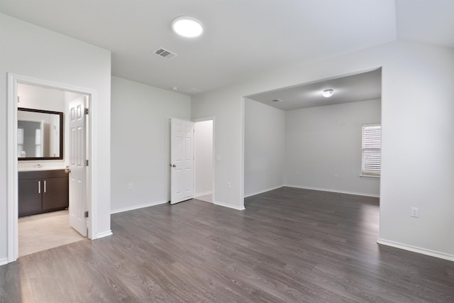 unfurnished bedroom with dark wood-type flooring, visible vents, and baseboards