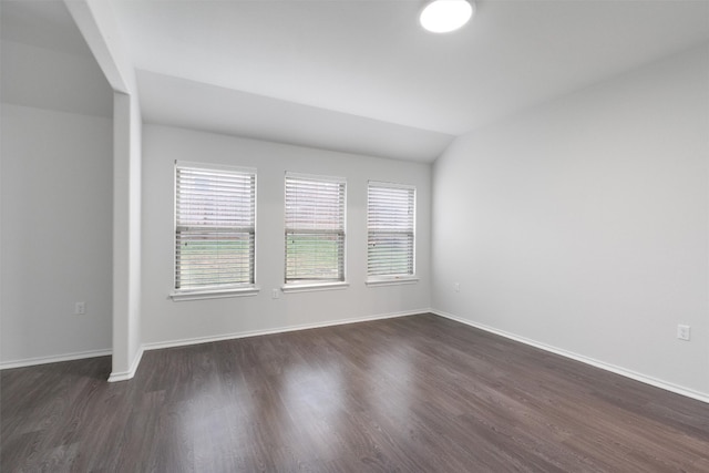 unfurnished room with dark wood-style flooring, vaulted ceiling, and baseboards