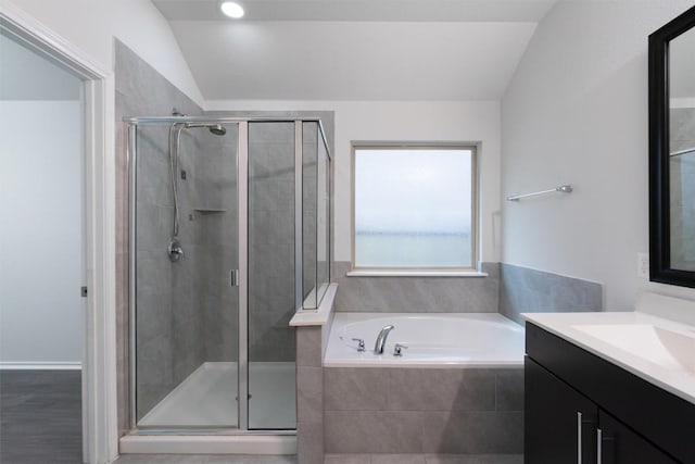 bathroom with a stall shower, lofted ceiling, vanity, and a bath