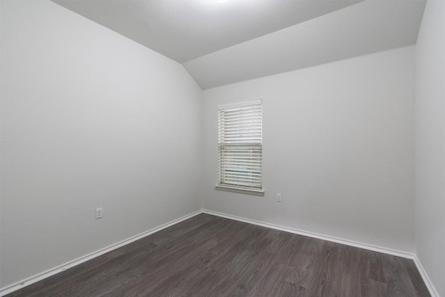 unfurnished room featuring lofted ceiling, baseboards, and dark wood-style flooring