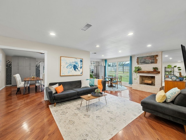 living room with light wood finished floors, a fireplace, visible vents, and recessed lighting