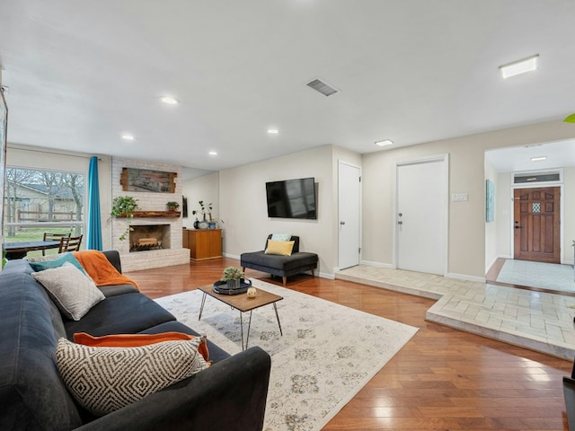 living room with recessed lighting, a fireplace, wood finished floors, visible vents, and baseboards