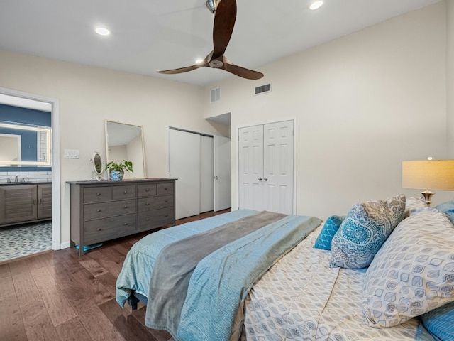 bedroom with multiple closets, lofted ceiling, recessed lighting, a sink, and wood finished floors