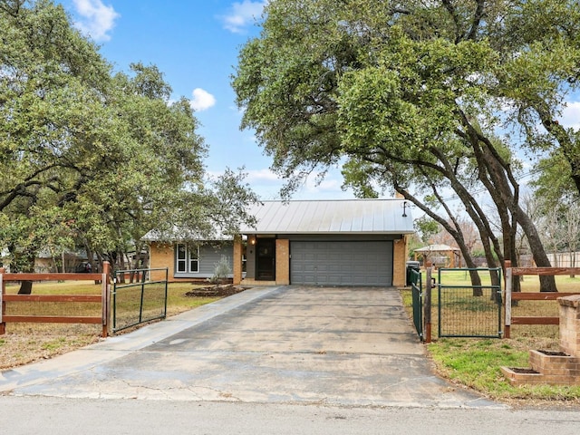 ranch-style house featuring an attached garage, fence, and a gate