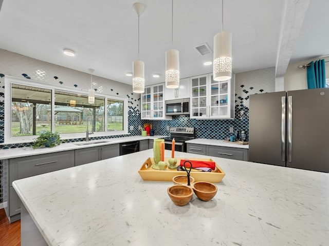 kitchen featuring stainless steel appliances, gray cabinets, visible vents, backsplash, and a sink