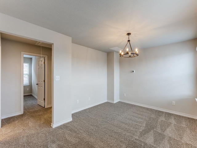 carpeted spare room featuring an inviting chandelier, attic access, and baseboards