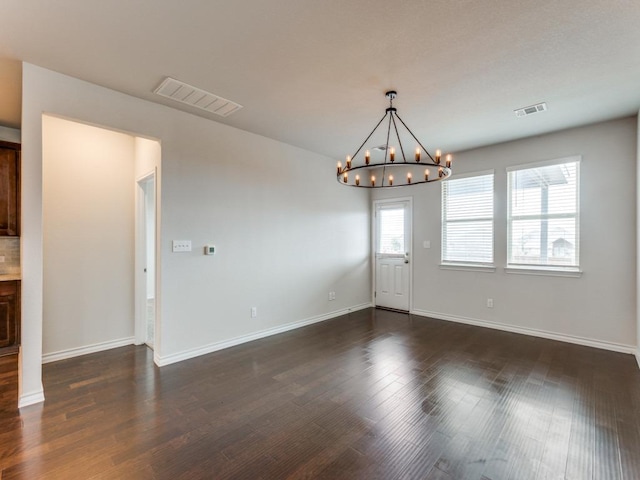 unfurnished dining area featuring dark wood-style floors, visible vents, and a chandelier