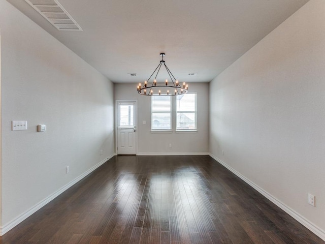 empty room featuring visible vents, dark wood finished floors, baseboards, and an inviting chandelier