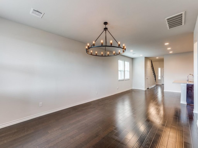 empty room featuring dark wood-style flooring, visible vents, and baseboards