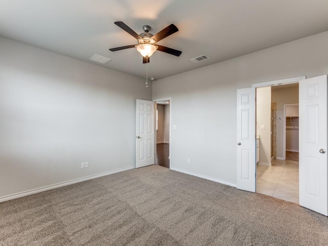 empty room with baseboards, visible vents, a ceiling fan, and light colored carpet