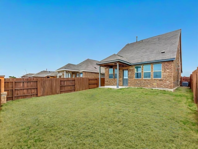 rear view of property featuring brick siding, a lawn, a patio area, and a fenced backyard