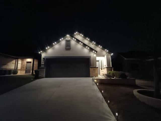 view of front facade featuring a garage, stone siding, concrete driveway, and stucco siding