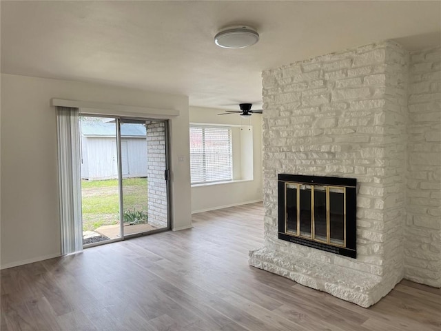 unfurnished living room with a ceiling fan, a fireplace, baseboards, and wood finished floors