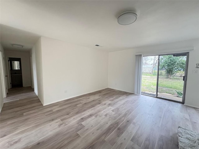 spare room featuring visible vents, baseboards, and wood finished floors