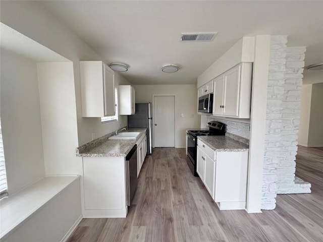 kitchen featuring visible vents, stainless steel appliances, light wood-type flooring, white cabinetry, and a sink