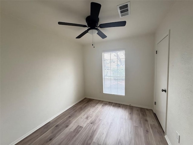 unfurnished room with a ceiling fan, wood finished floors, visible vents, and baseboards