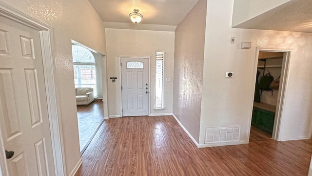 entryway with a textured wall, wood finished floors, visible vents, and baseboards