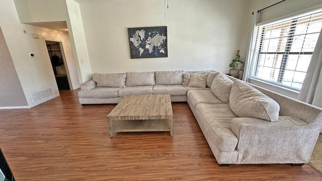 living room with baseboards, visible vents, and wood finished floors