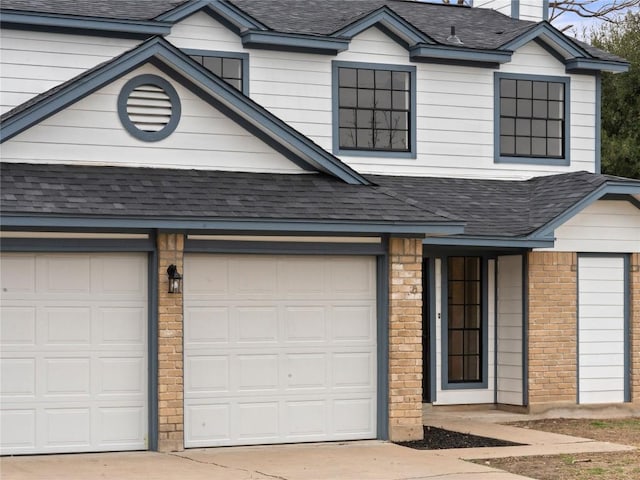 view of front of home with a shingled roof, brick siding, driveway, and an attached garage