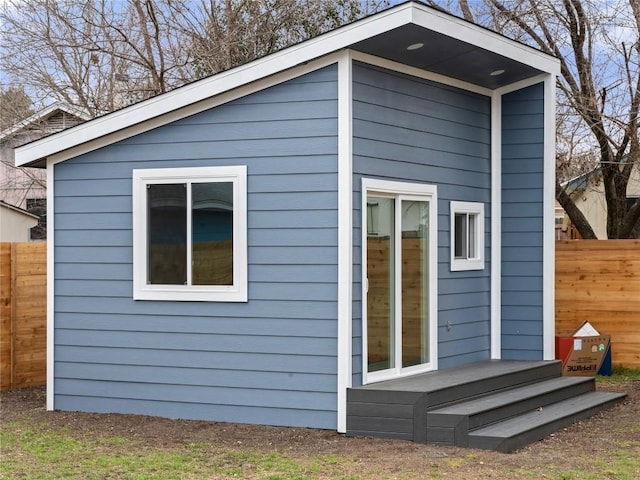 view of outbuilding featuring fence and an outdoor structure