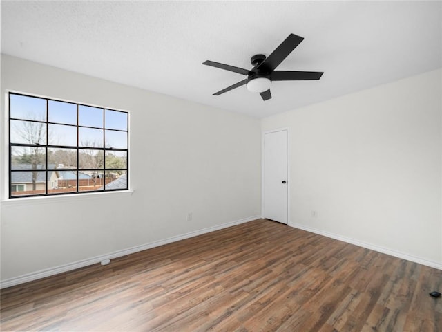 empty room featuring a ceiling fan, baseboards, and wood finished floors