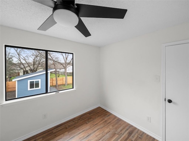 spare room with a ceiling fan, a textured ceiling, baseboards, and wood finished floors