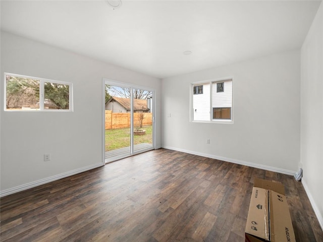 empty room with dark wood-style flooring and baseboards